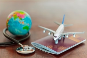 Close up of a miniature plane, globe, passport and stethoscope