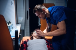 Male EMS professional placing an oxygen mask on a woman