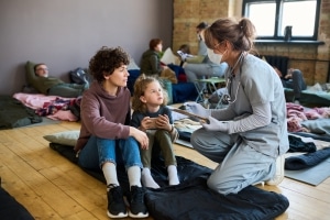 Medical professional kneeling next to a homeless woman and child