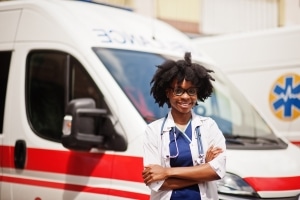 Smiling African-American EMS professional in front of an ambulance